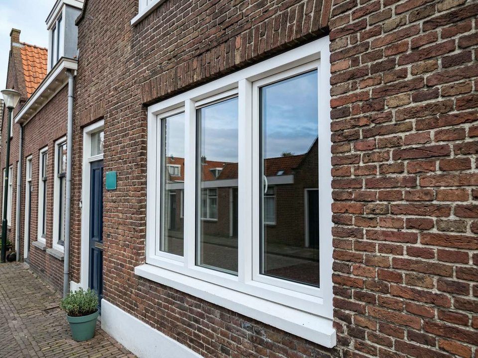 Nieuw kozijn met isolerend glas in de bakstenen gevel van een woning